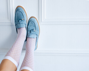 Stylish suede light blue loafers at the girl's feet. Fashionable and stylish shoes and beautiful shoes.