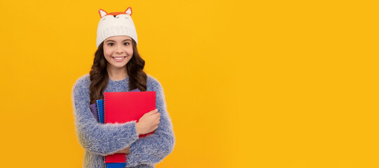 Poster - Winter school. sweater and hat hold workbook on yellow background. Portrait of schoolgirl student, studio banner header. School child face, copyspace.