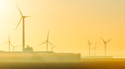 Wall Mural - Wind turbines in a foggy agricultural field in sunlight at sunrise in autumn, Almere, Flevoland, Netherlands, September, 2022