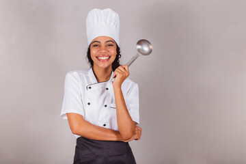 young black Brazilian woman, cook. Holding kitchen ladle for preparing broths and soups.