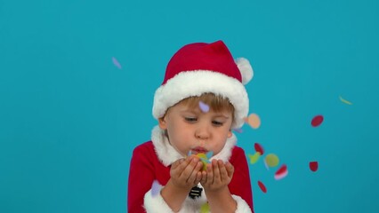 Canvas Print - Happy child blowing confetti. Funny kid wearing Christmas costume against blue background. Xmas holiday concept. Slow motion