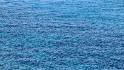 Genova, Italy- July 27, 2022:Panorama of the blue sea, light above the water, ocean sunrise. Some little waves in winter days. Clear sky reflected on the water.