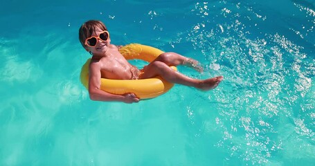 Wall Mural - Happy child having fun on summer vacation. Kid playing in swimming pool. Active healthy lifestyle concept. Slow motion