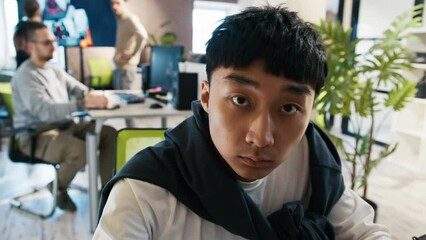 An Asian and European man looks at the camera as if in a monitor in an office for the development of games and computer applications.