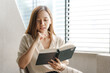© NanSan - Portrait of confident pretty asian woman reading a book while relaxing.