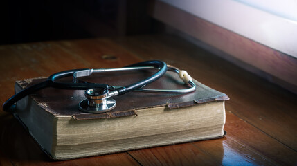 Wall Mural - Stethoscope and the Bible on wooden table, concept for treatment, science and religion, with copy space , space for text.