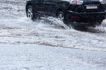 Wall Mural - car splashes through a flooded road during heavy rain