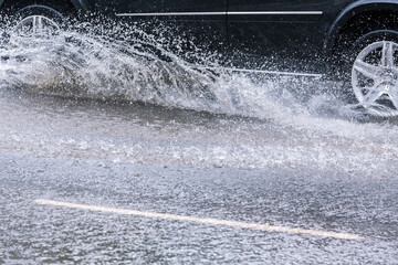 Wall Mural - car splashes through a large puddle on a wet road. driving in heavy rain.