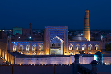 Wall Mural - The old madrasah of Muhammad Rahim Khan in the backlight in the urban nightscape. Ichan-Kala, Hiva. Uzbekistan.