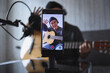 © Gatot - Asian influencer playing guitar during podcast or live video broadcast for the audience from the mobile phone at home