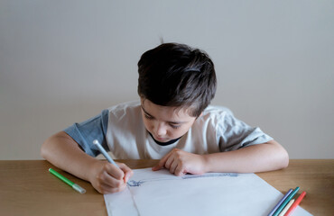 Wall Mural - School kid using grey colour pen drawing or sketching on paper,Portrait  boy siting on table doing homework in living room,Child enjoy art and craft activity at home on weekend,Education concept