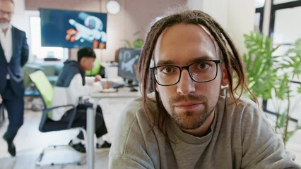 CEO of company and European man discusses something and looks at the camera as if in a monitor in an office for the development of games and computer applications.