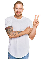 Wall Mural - Young irish man wearing casual clothes smiling with happy face winking at the camera doing victory sign. number two.