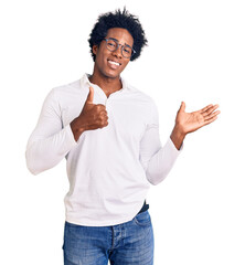 Handsome african american man with afro hair wearing casual clothes and glasses showing palm hand and doing ok gesture with thumbs up, smiling happy and cheerful