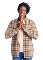 Canvas Print - Handsome african american man with afro hair wearing casual clothes and glasses praying with hands together asking for forgiveness smiling confident.