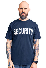 Poster - Young handsome man wearing security t shirt in shock face, looking skeptical and sarcastic, surprised with open mouth