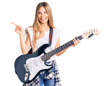 Beautiful Caucasian Woman With Blonde Hair Playing Electric Guitar Smiling Happy Pointing With Hand And Finger To The Side