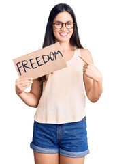 Poster - Young beautiful caucasian woman holding freedom banner smiling happy pointing with hand and finger