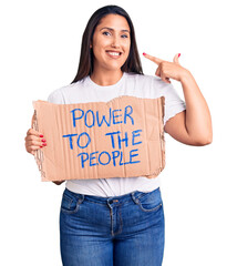 Poster - Young beautiful woman holding power to the people cardboard banner pointing finger to one self smiling happy and proud