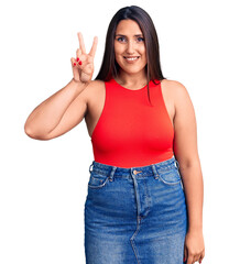 Poster - Young beautiful brunette woman wearing casual sleevelss t-shirt smiling with happy face winking at the camera doing victory sign. number two.