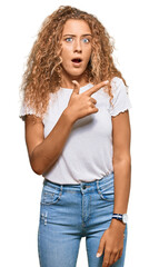 Sticker - Beautiful caucasian teenager girl wearing casual white tshirt surprised pointing with finger to the side, open mouth amazed expression.