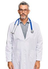 Sticker - Middle age grey-haired man wearing doctor uniform and stethoscope with serious expression on face. simple and natural looking at the camera.