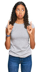 Wall Mural - Young african american girl wearing casual clothes pointing up looking sad and upset, indicating direction with fingers, unhappy and depressed.