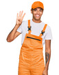 © Krakenimages.com - Young handsome african american man wearing handyman uniform showing and pointing up with fingers number four while smiling confident and happy.