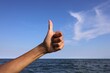 © ChiccoDodiFC - hand with thumb up pointing up ok sign all right and the sea
