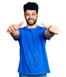 © Krakenimages.com - Young arab man with beard wearing casual blue t shirt approving doing positive gesture with hand, thumbs up smiling and happy for success. winner gesture.