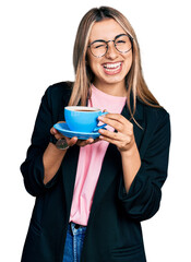 Wall Mural - Hispanic young woman drinking a cup of coffee winking looking at the camera with sexy expression, cheerful and happy face.