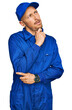 © Krakenimages.com - Bald man with beard wearing builder jumpsuit uniform thinking worried about a question, concerned and nervous with hand on chin