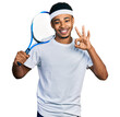 © Krakenimages.com - Young african american man playing tennis holding racket doing ok sign with fingers, smiling friendly gesturing excellent symbol