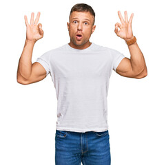 Poster - Handsome muscle man wearing casual white tshirt looking surprised and shocked doing ok approval symbol with fingers. crazy expression