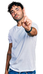 Sticker - Hispanic young man with beard wearing casual white t shirt pointing with finger up and angry expression, showing no gesture