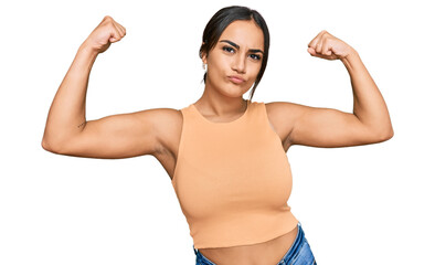 young brunette woman wearing casual clothes showing arms muscles smiling proud. fitness concept.