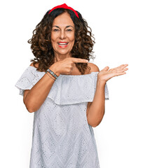 Sticker - Middle age hispanic woman wearing casual clothes amazed and smiling to the camera while presenting with hand and pointing with finger.