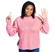 © Krakenimages.com - Beautiful hispanic woman wearing casual winter sweater showing and pointing up with fingers number six while smiling confident and happy.