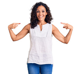 Middle age beautiful woman wearing casual sleeveless t shirt looking confident with smile on face, pointing oneself with fingers proud and happy.