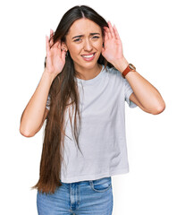 Poster - Young hispanic girl wearing casual white t shirt trying to hear both hands on ear gesture, curious for gossip. hearing problem, deaf