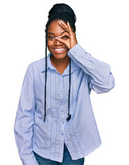 Sticker - Young african american woman wearing casual clothes doing ok gesture with hand smiling, eye looking through fingers with happy face.