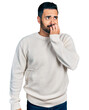 © Krakenimages.com - Young hispanic man with beard wearing casual white sweater looking stressed and nervous with hands on mouth biting nails. anxiety problem.