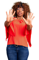 Sticker - Young african american woman wearing casual clothes afraid and terrified with fear expression stop gesture with hands, shouting in shock. panic concept.