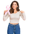 © Krakenimages.com - Young brunette woman holding pink cancer ribbon pointing finger to one self smiling happy and proud