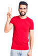© Krakenimages.com - Young handsome man with beard wearing casual t-shirt showing and pointing up with fingers number two while smiling confident and happy.