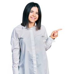 Poster - Young brunette woman with blue eyes wearing oversize white shirt with a big smile on face, pointing with hand finger to the side looking at the camera.