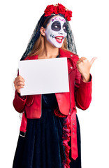 Sticker - Woman wearing day of the dead costume holding blank empty banner pointing thumb up to the side smiling happy with open mouth