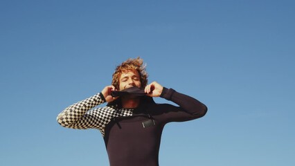 Wall Mural - Good looking guy wearing wetsuit while preparing for the surfing training