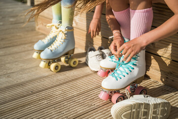 Wall Mural - Two child girls in high socks tying laces at their roller skates while preparing for the riding