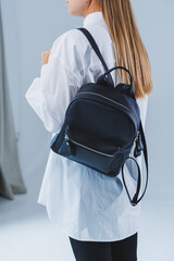 Wall Mural - Black leather backpack in a woman's hand. A man with a luxurious leather backpack. Women's bags